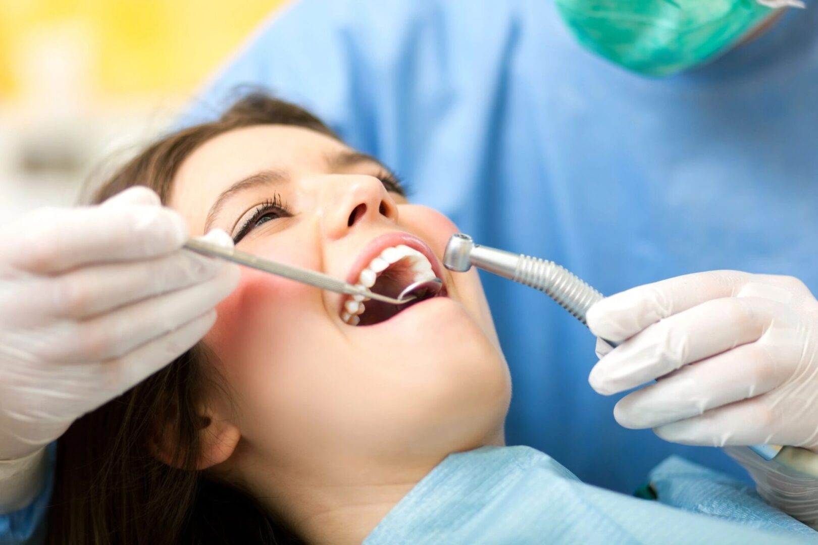 A woman is getting her teeth cleaned by dentist.