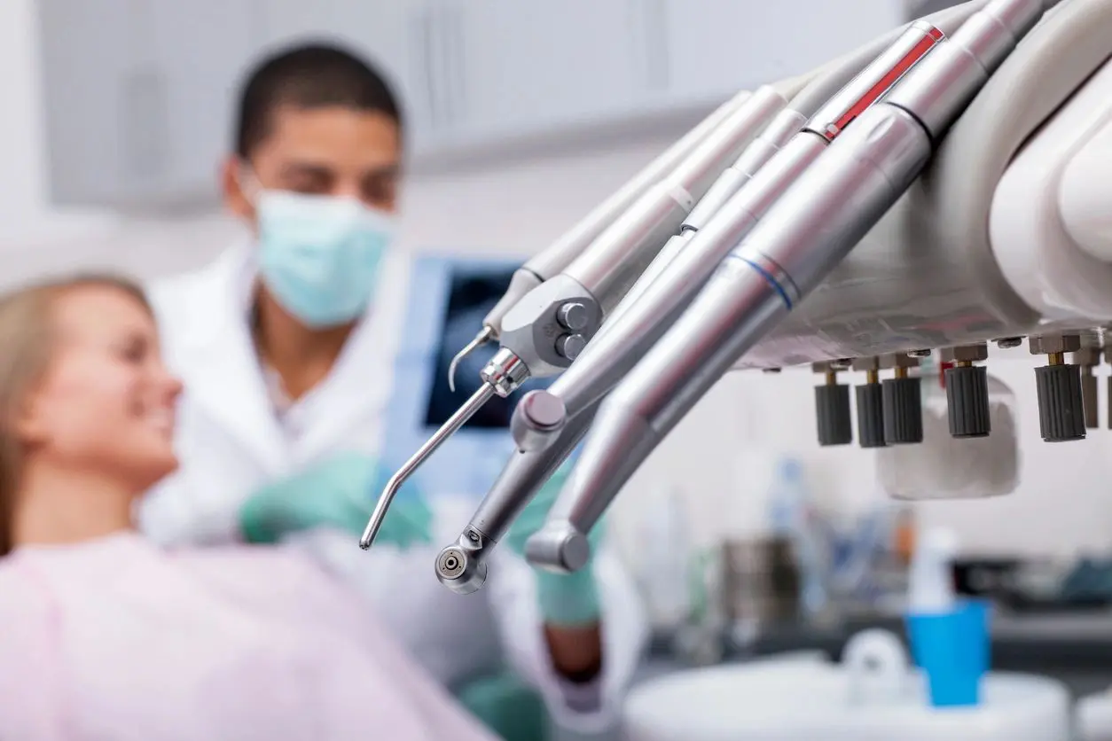 A dentist is working on an implant in the background.