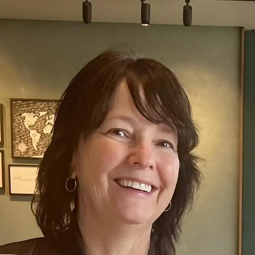 A woman smiling for the camera in front of a wall.